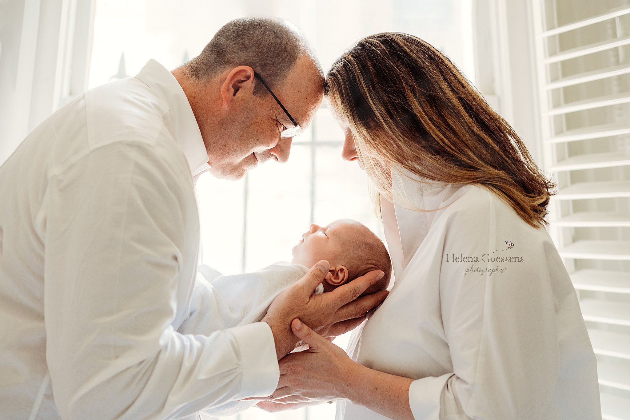 mom and dad stand with foreheads touching looking down at baby boy during South End newborn session