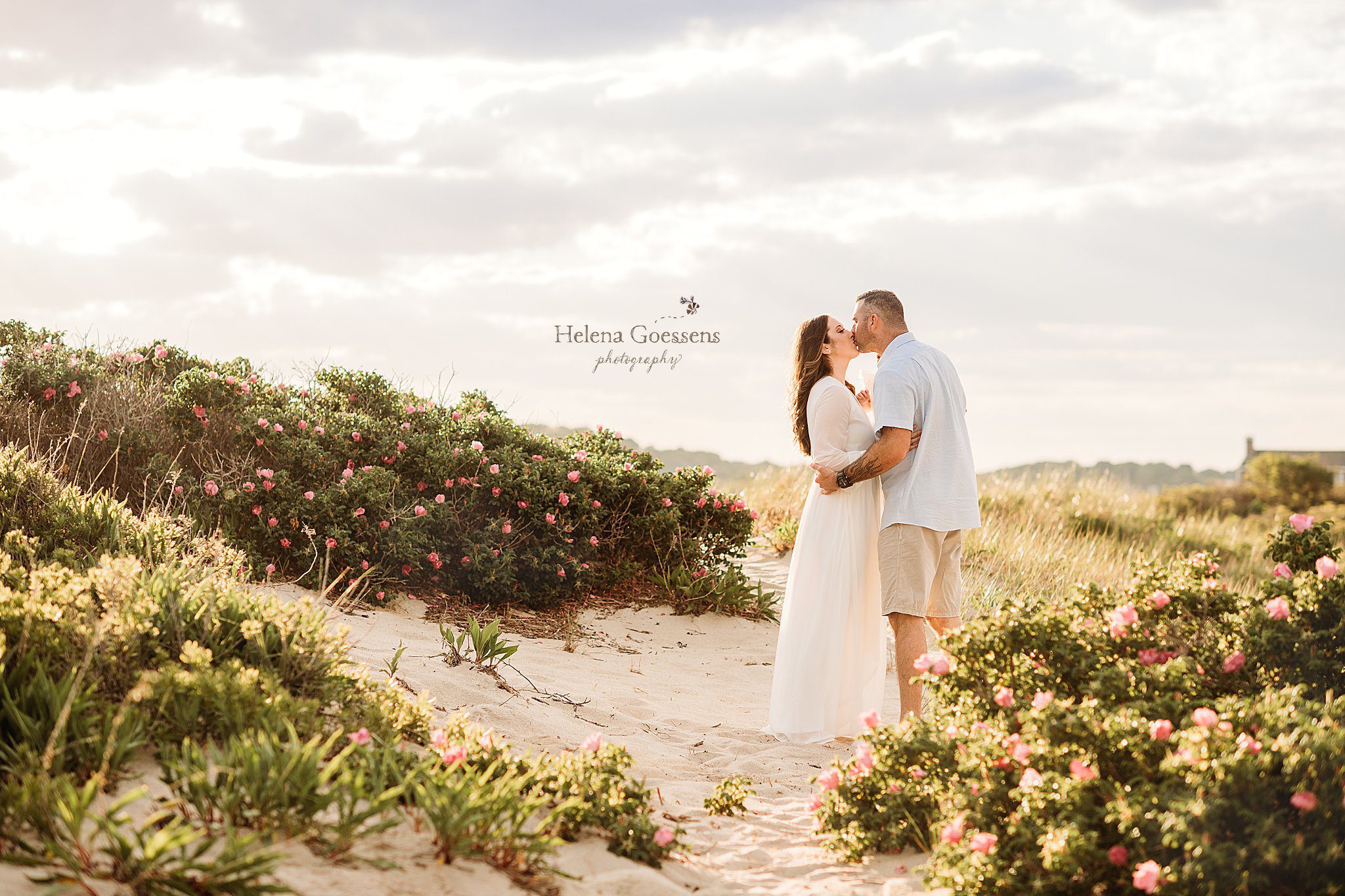 parents kiss among pink flowers at Rexhame Beach in MA