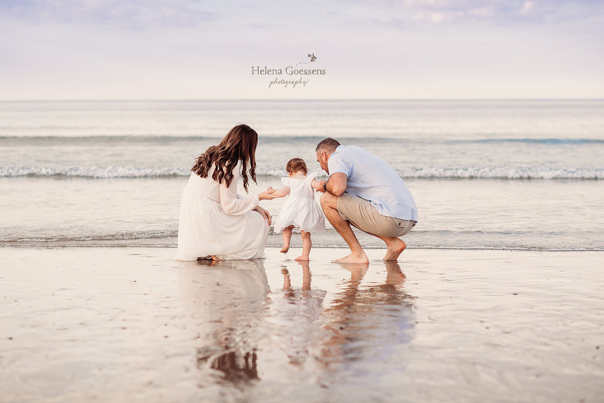 parents kneel in front of ocean with toddler girl during Rexhame Beach family session
