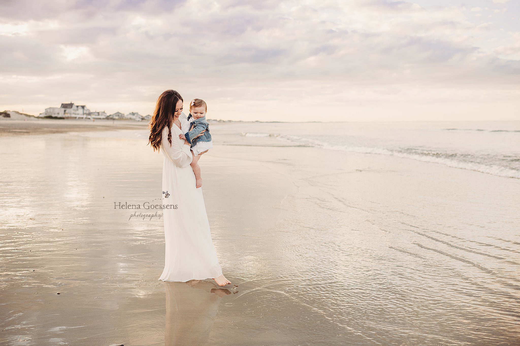 mom walks through water with baby girl during Rexhame Beach family session