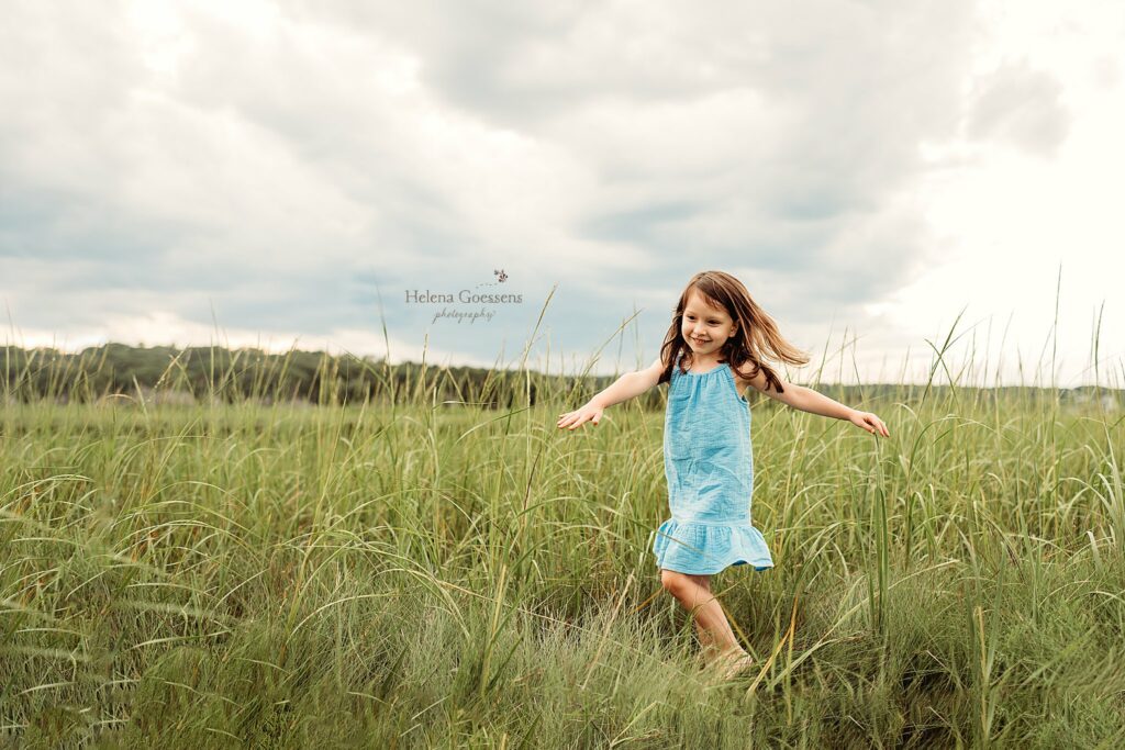 toddler girl twirls in tall grass of Rexhame Beach 
