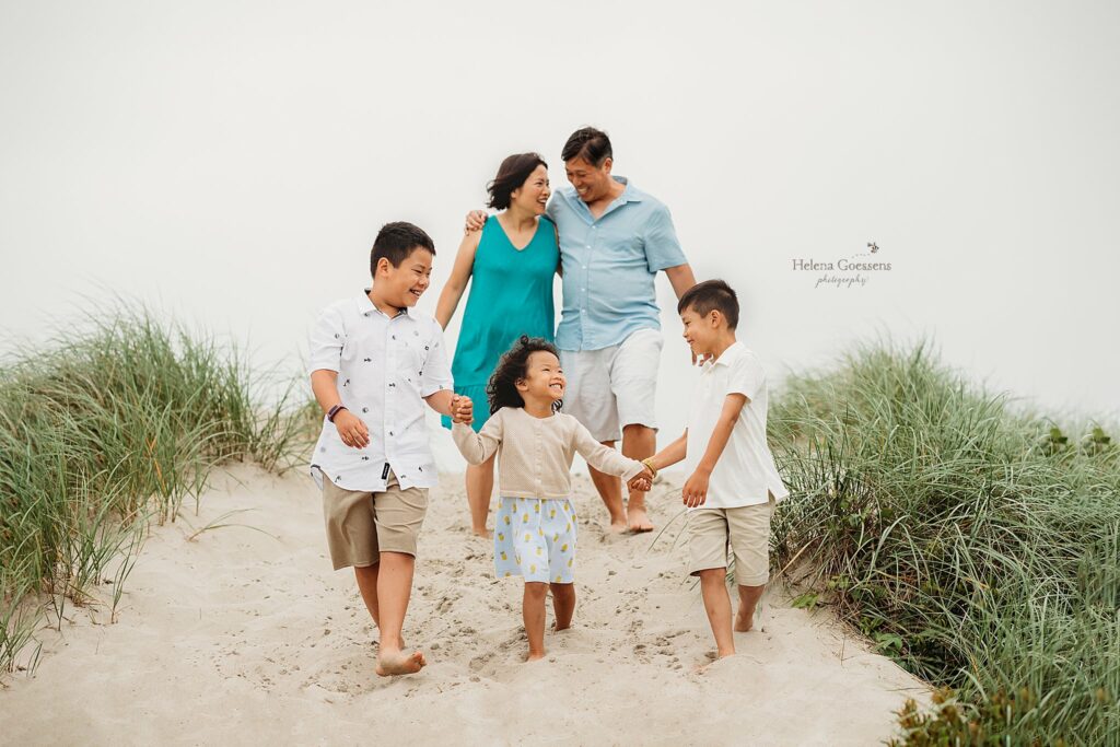 parents walk on dunes with three kids during family photos in Marshfield MA
