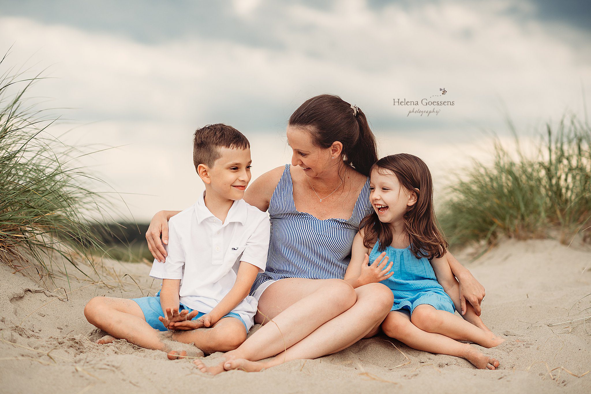 mom sits with two children during Rexhame Beach Family Photos on beach dunes 