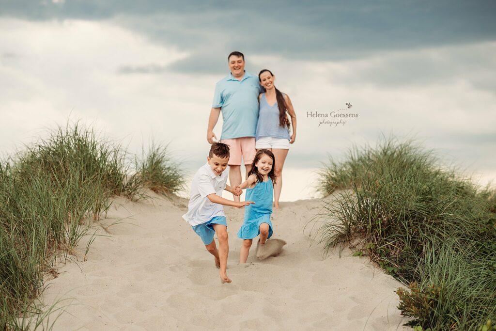 parents pose on top of dunes while kids run down during Rexhame Beach Family Photos 