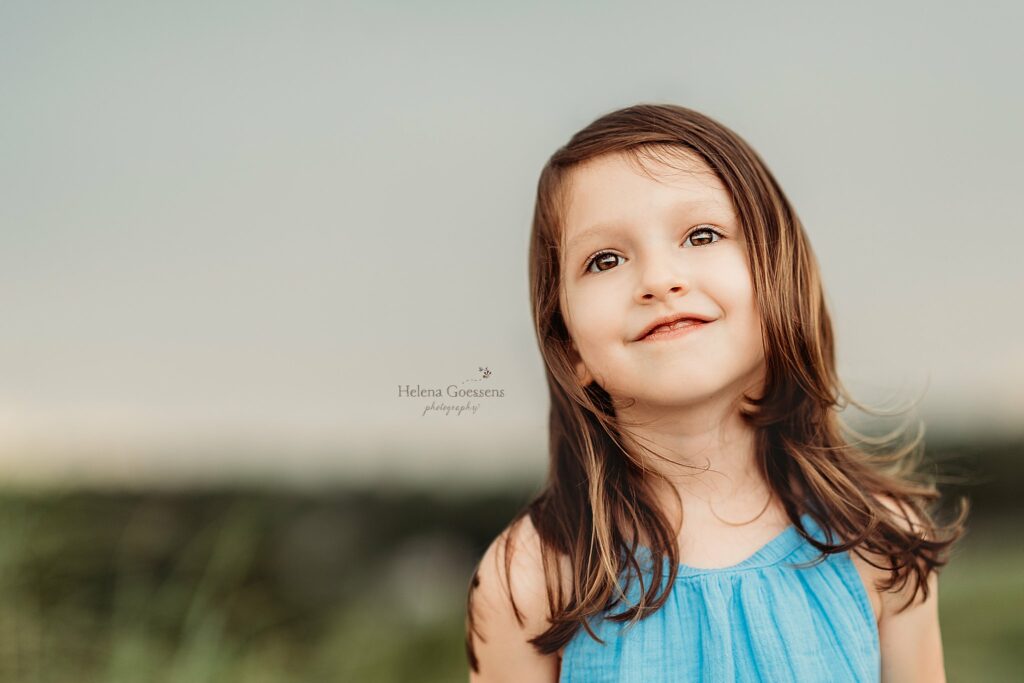 toddler in blue dress smiles at MA family photographer 