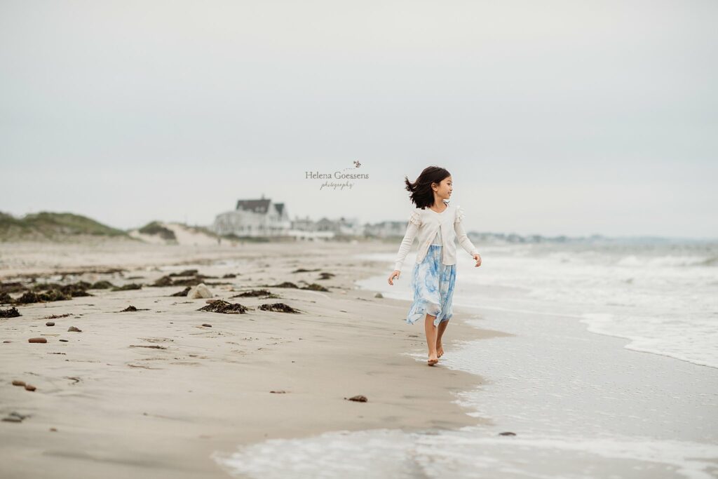 young girl in blue dress walks along ocean on Rexhame Beach 