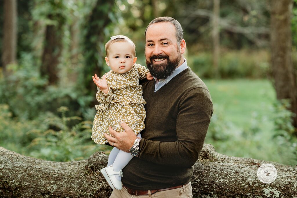 dad holds 9 month old during family portraits in Larz Anderson Park