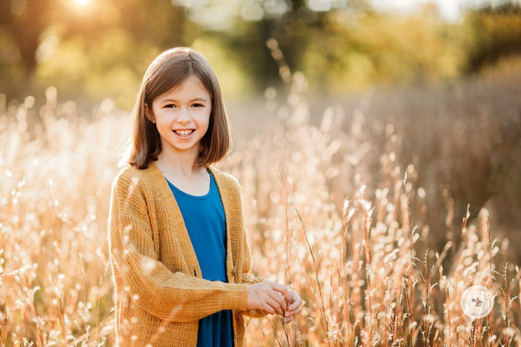 girl plays in field during fall family photos in Concord MA
