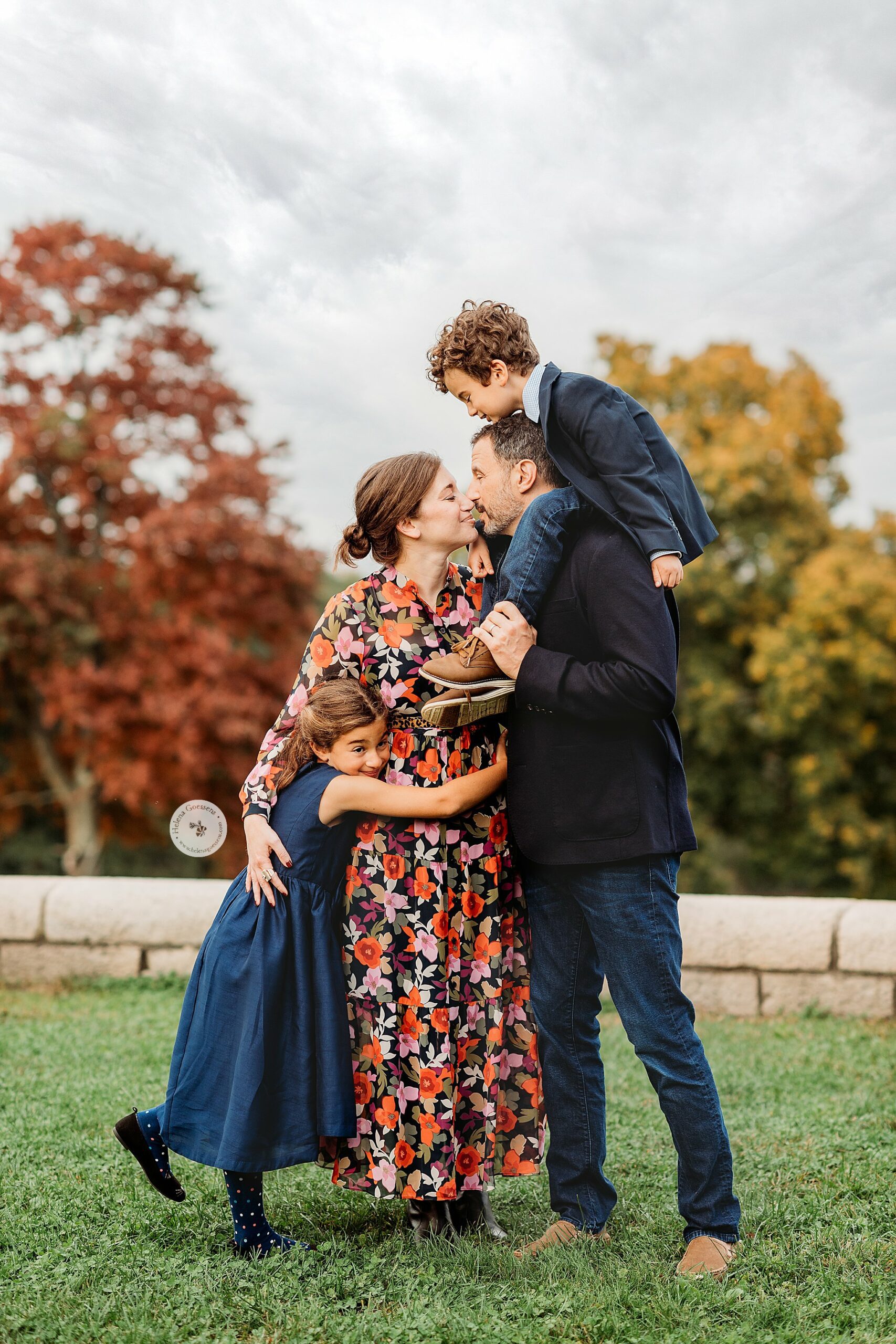 parents lean for kiss with two kids hugging them during Brookline MA Family Portraits
