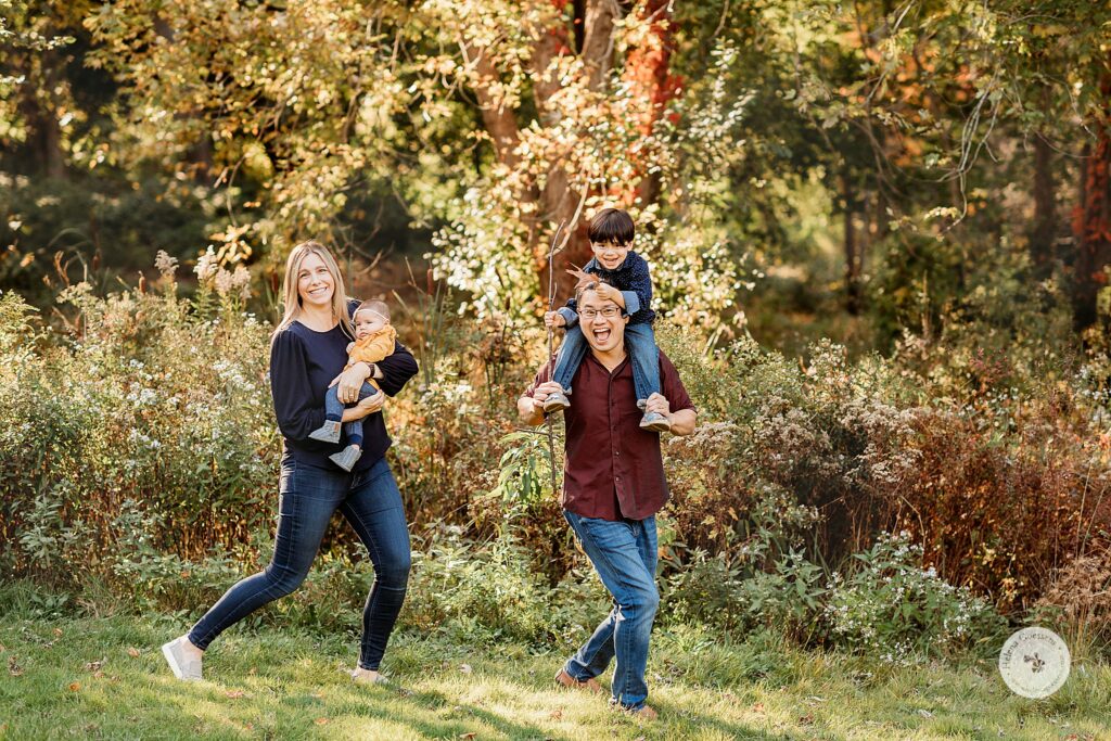parents run with kids during fall Larz Anderson Park family photos