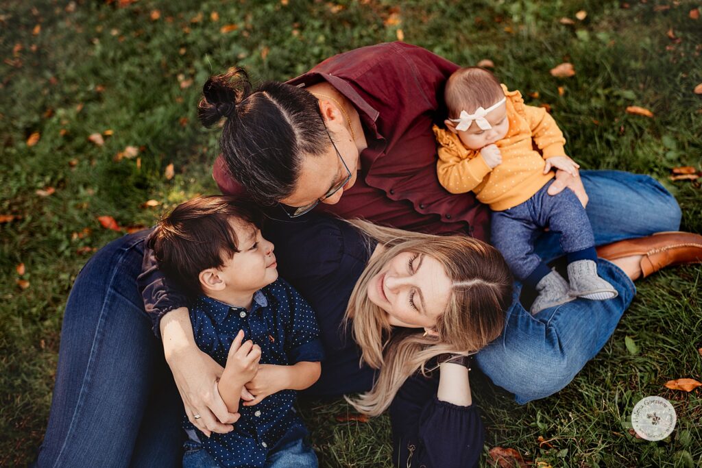 parents lay on grass with two kids during fall Larz Anderson Park family photos