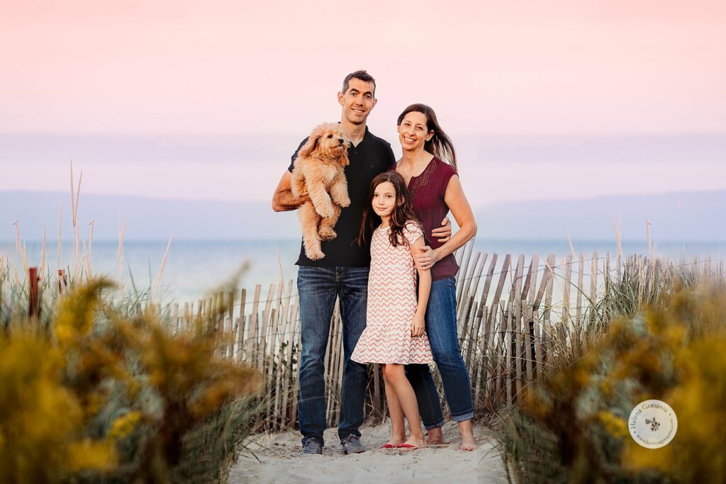family of three poses with new puppy during sunset Rexhame Beach family photos
