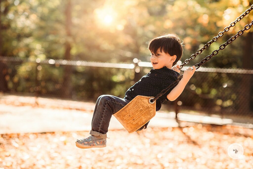 young boy swings during family photos in Brookline MA