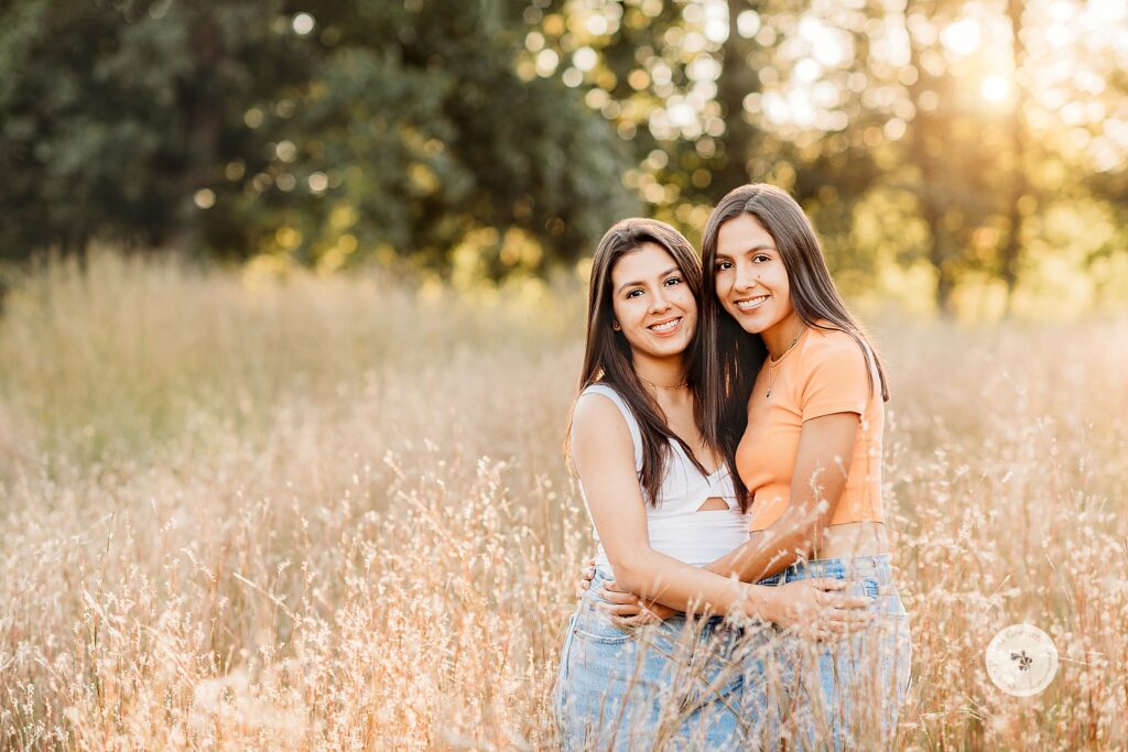twin sisters hug in tall grass at The Old Manse Family Portraits