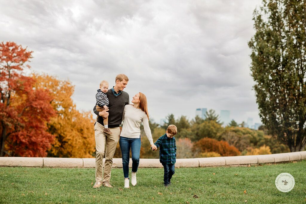 parents look at each other with two sons during Fall Family Portraits at Larz Anderson Park