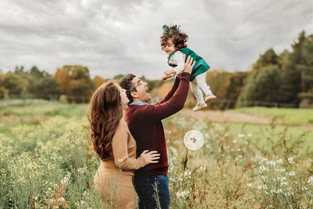 dad lifts daughter up during fall family photos