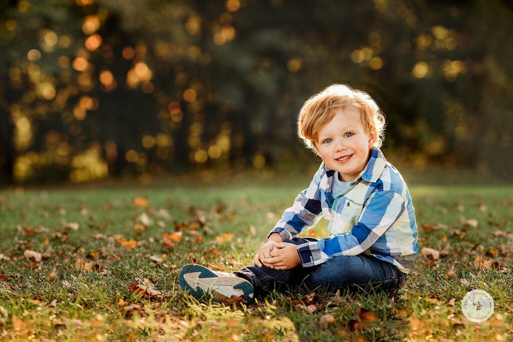 toddler sits in plaid shirt during MA family photos