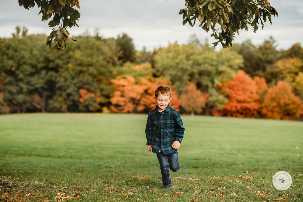 preschool son runs through park in Boston MA during the fall 