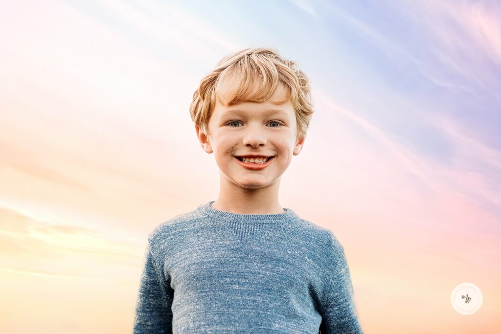 boy in blue shirt smiles during Sunset Family Portraits at Larz Anderson Park