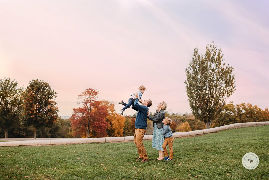 dad lifts son up during Sunset Family Portraits at Larz Anderson Park