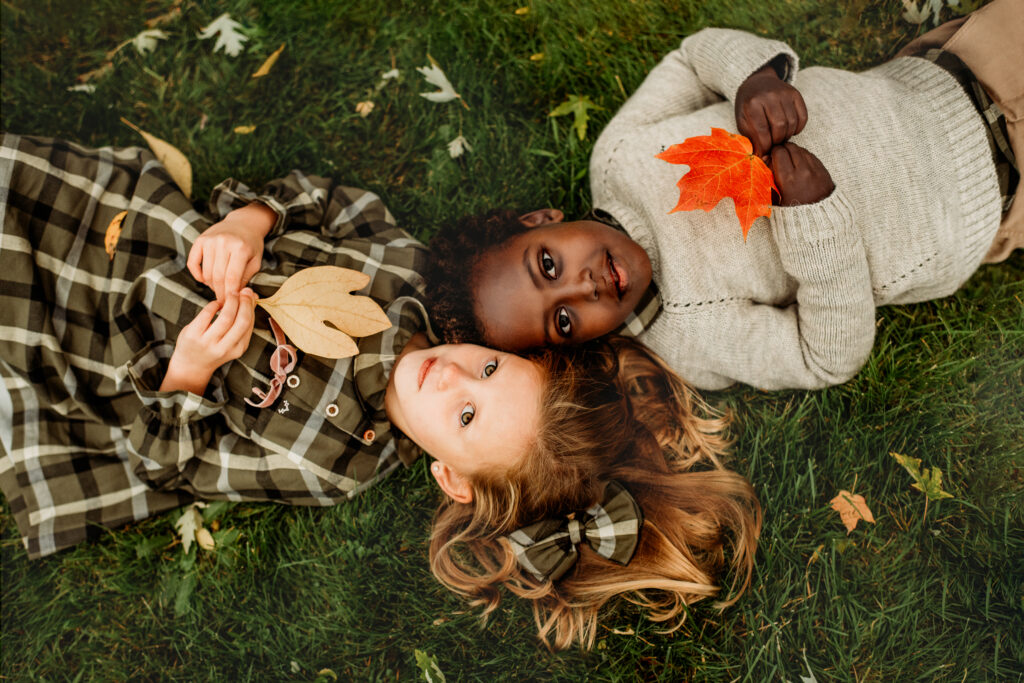 kids lay on grass holding leaves photographed by MA family photographer Helena Goessens Photography 