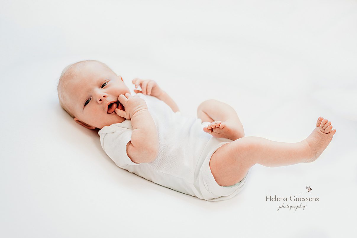 baby laughs laying on white sheet during lifestyle newborn portraits in Dedham MA