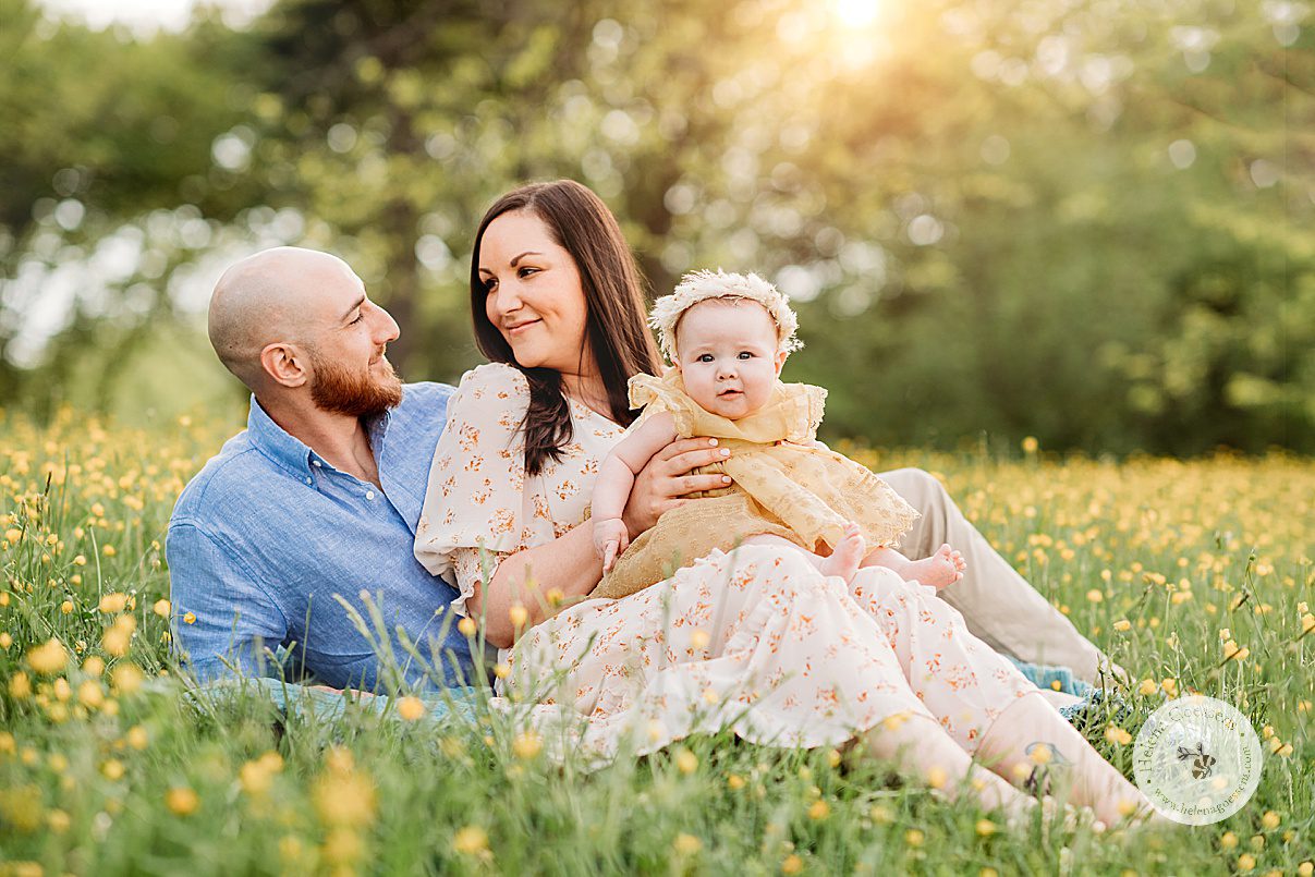 new parents sit together with daughter on their lap during family photos in Boston MA