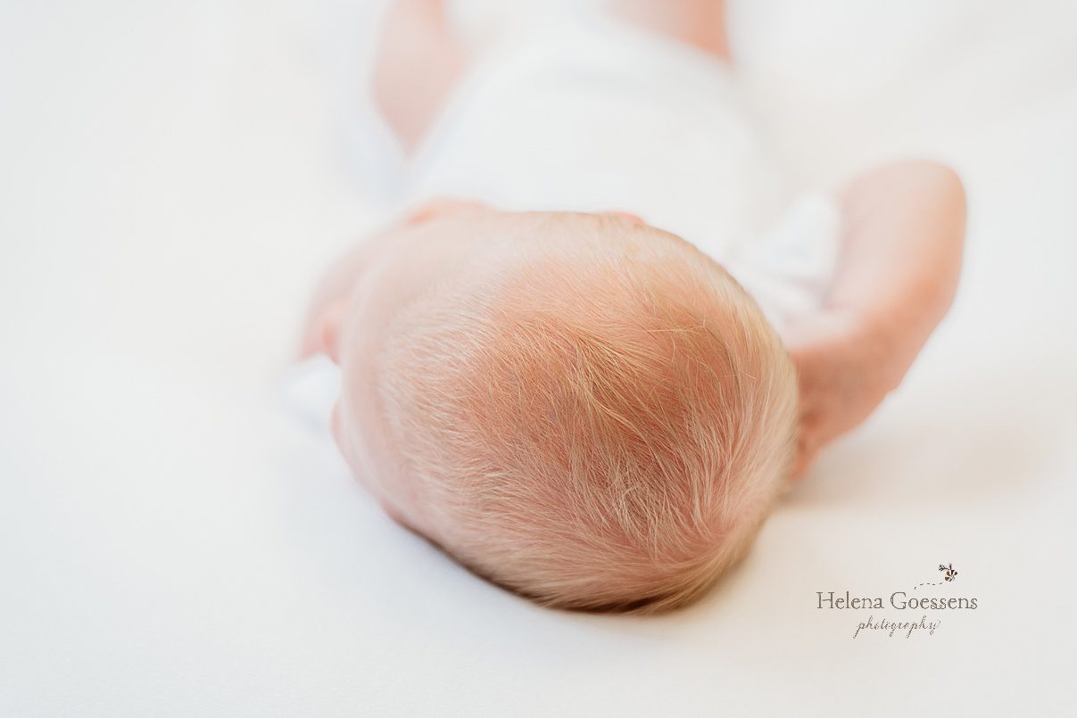 top of baby girl's head laying on bed during newborn photos at home 