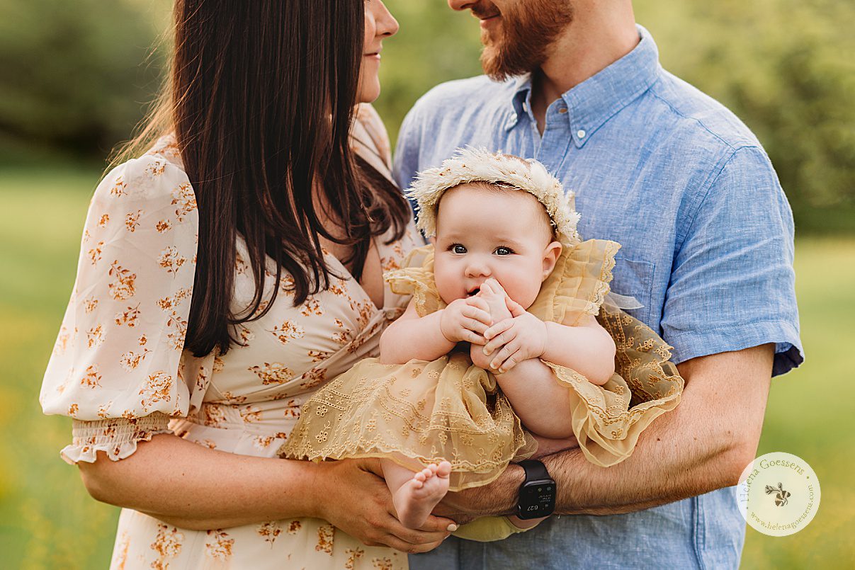 parents hold baby girl between them during spring family photos in Boston MA