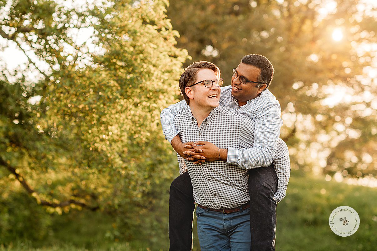 husband holds partner on his back during spring Jamaica Plain family portraits at sunset 