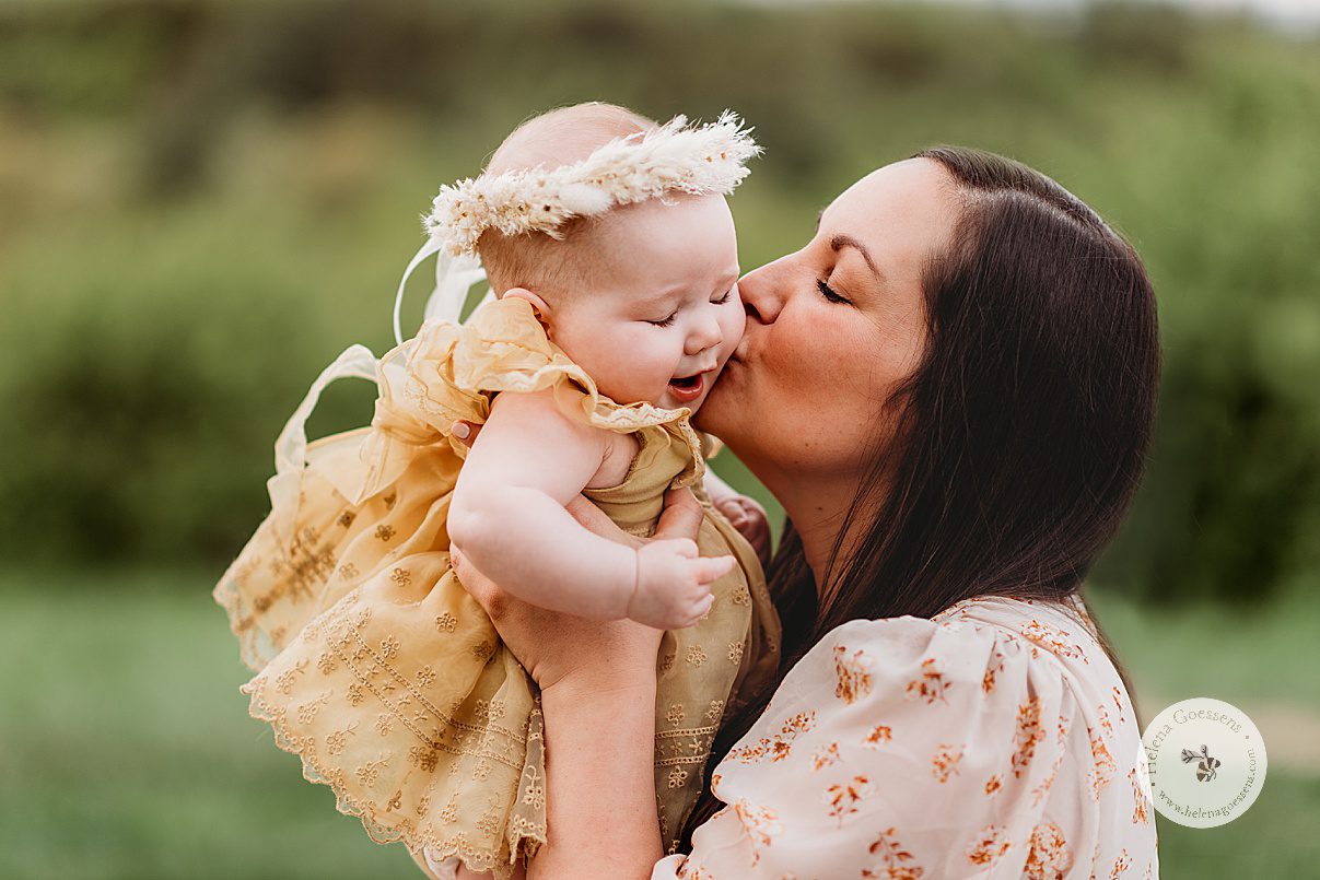 mom kisses baby girl on cheek during family photos in Jamaica Plain