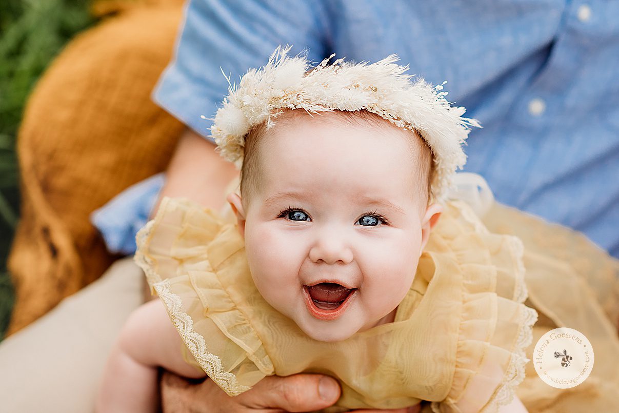 baby girl in yellow dress smiles at camera during Spring Family Portraits at Peter's Hill