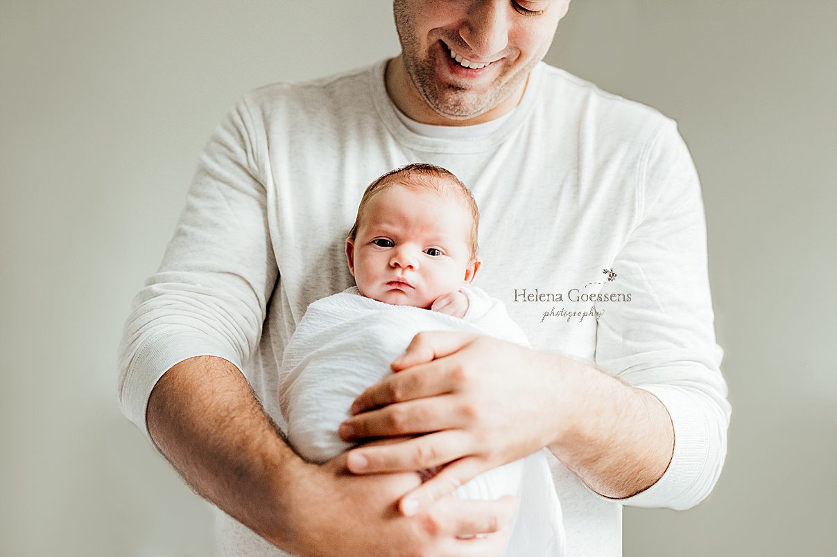 dad holds newborn baby girl in white wrap during Randolph MA newborn session