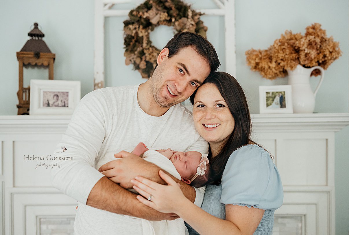 new parents hold baby girl in front of mantle during Randolph MA newborn session