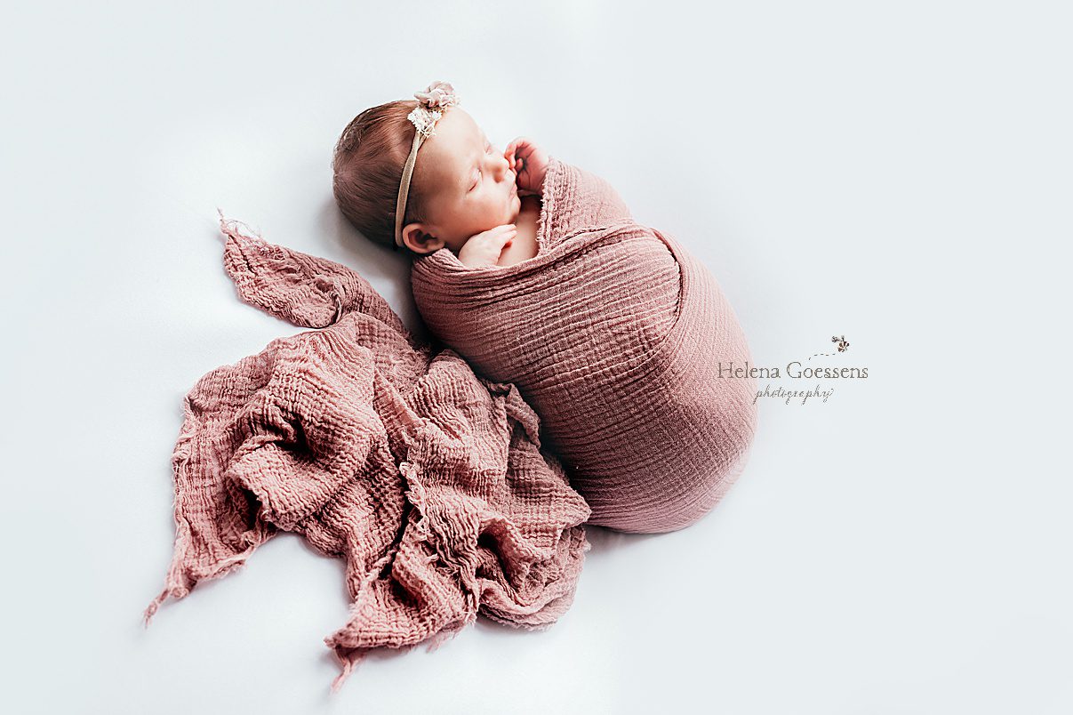 baby lays on white blanket with pink blanket during Randolph MA newborn session