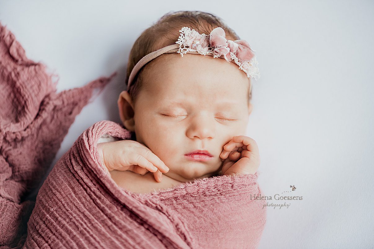 baby girl lays on pink blanket with headband during Randolph MA newborn session