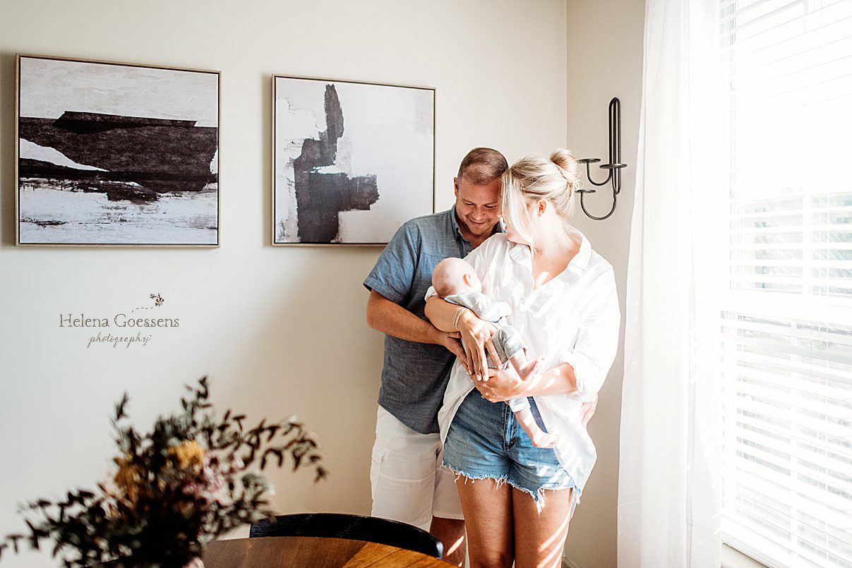 parents stand in dining room with baby boy during newborn session in Foxborough apartment