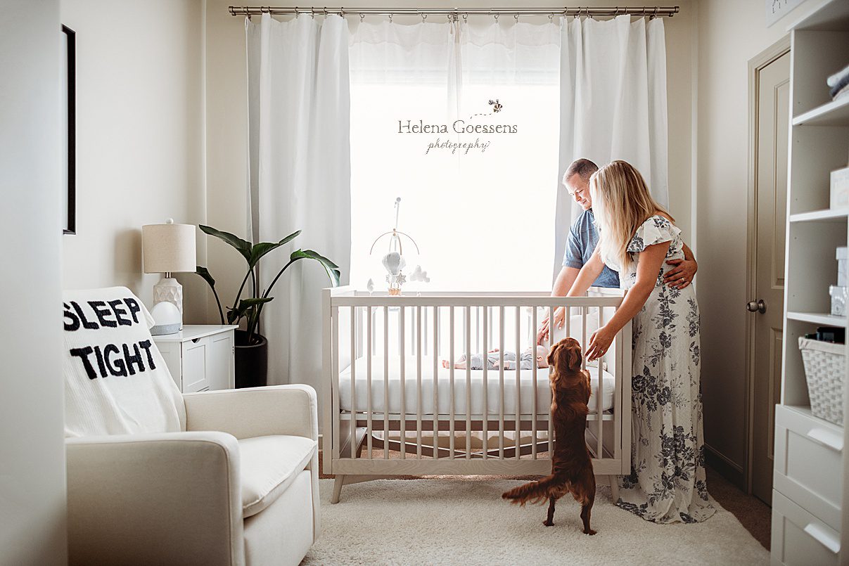 parents look down at bay in crib during newborn session in Foxborough apartment