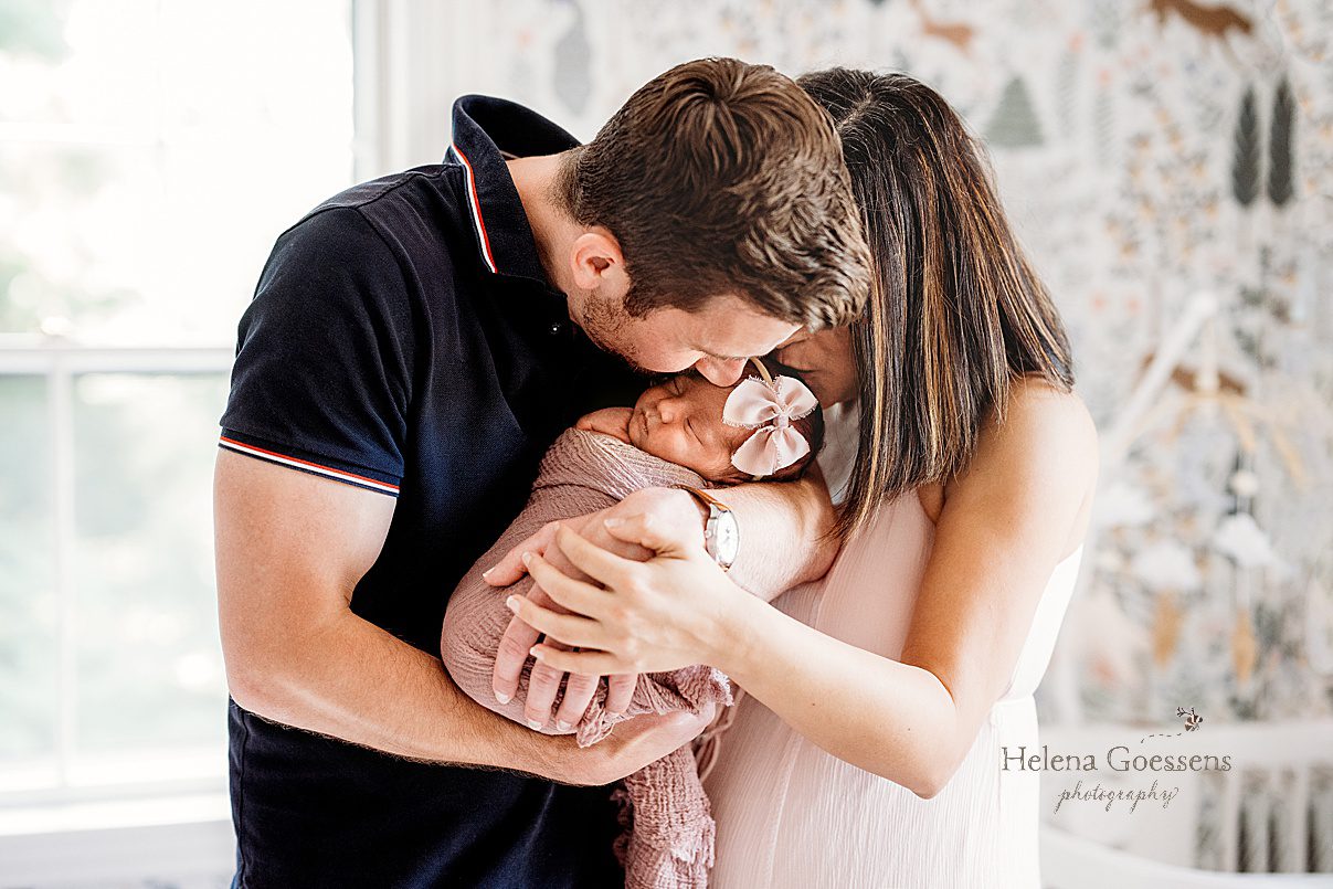 mom and dad hug newborn girl in nursery during Dedham MA lifestyle newborn portraits 