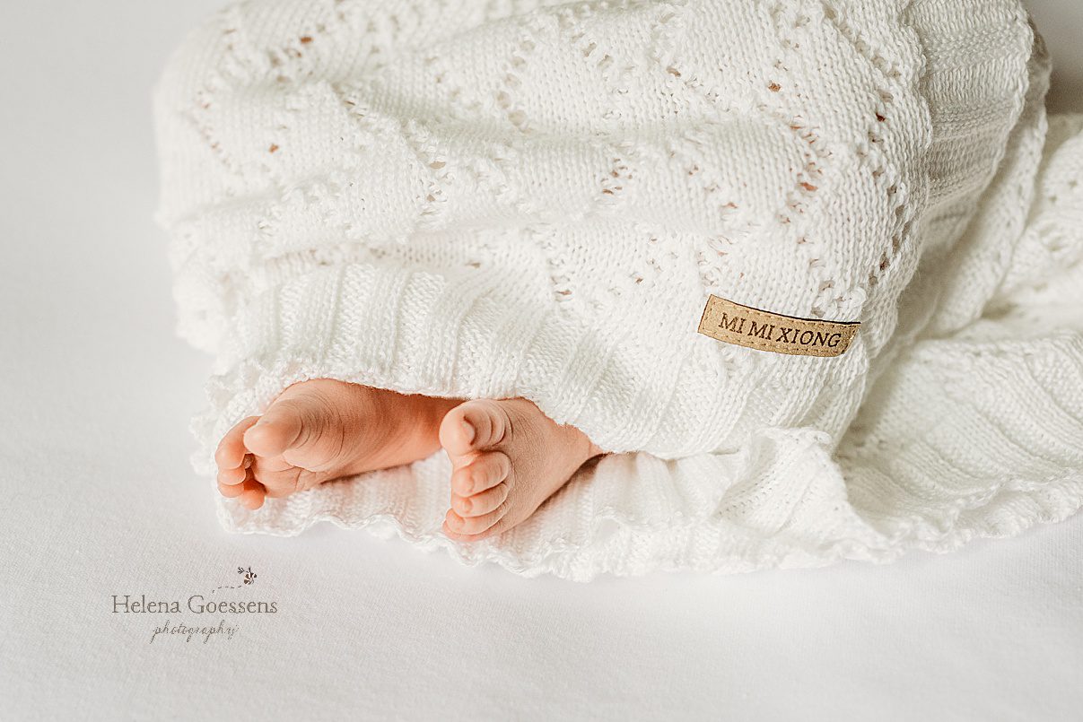 baby's toes peek out of white knit blanket during lifestyle newborn session in Newton