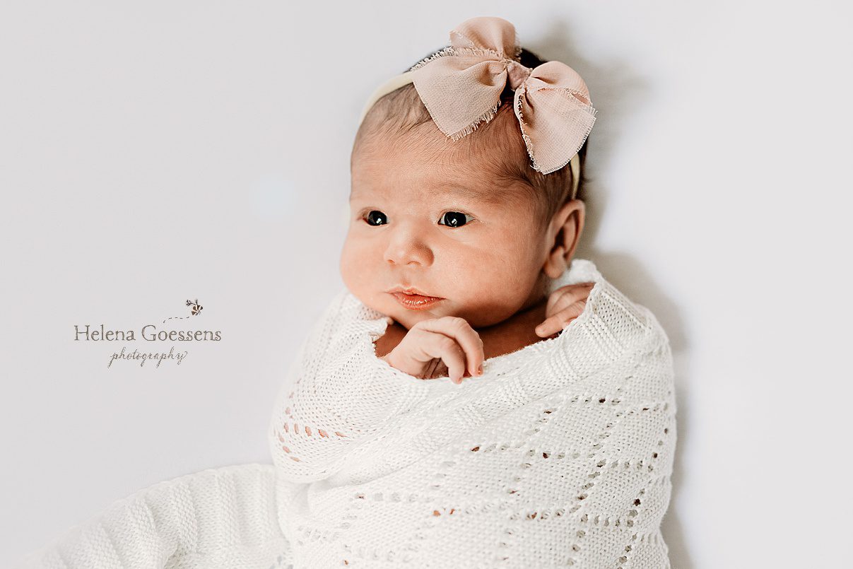 baby girl lays in knit wrap with pink bow during Dedham MA lifestyle newborn portraits 