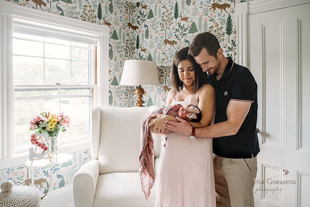 new parents look down at baby girl during Dedham MA lifestyle newborn portraits in nursery 