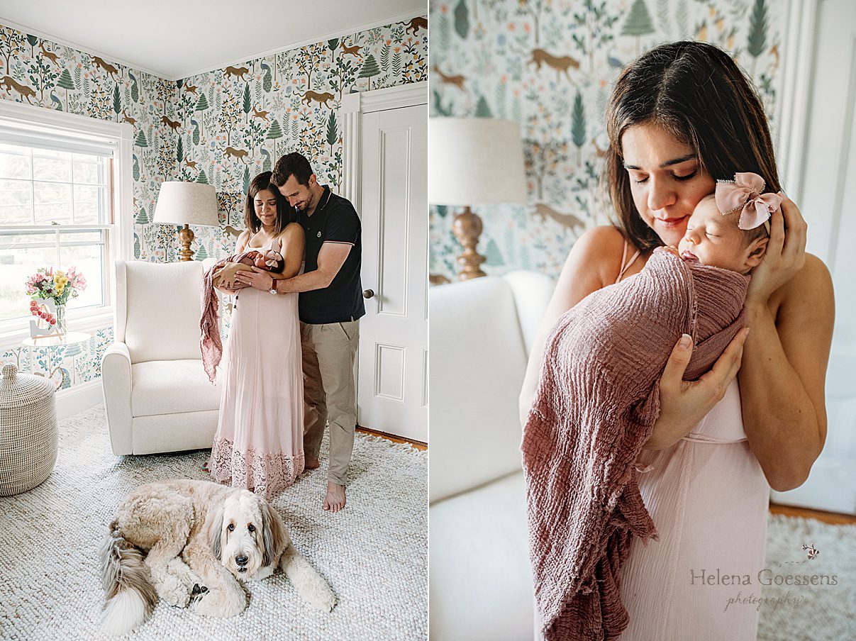 parents hold newborn baby girl in mauve wrap with dog sitting by them in nursery 