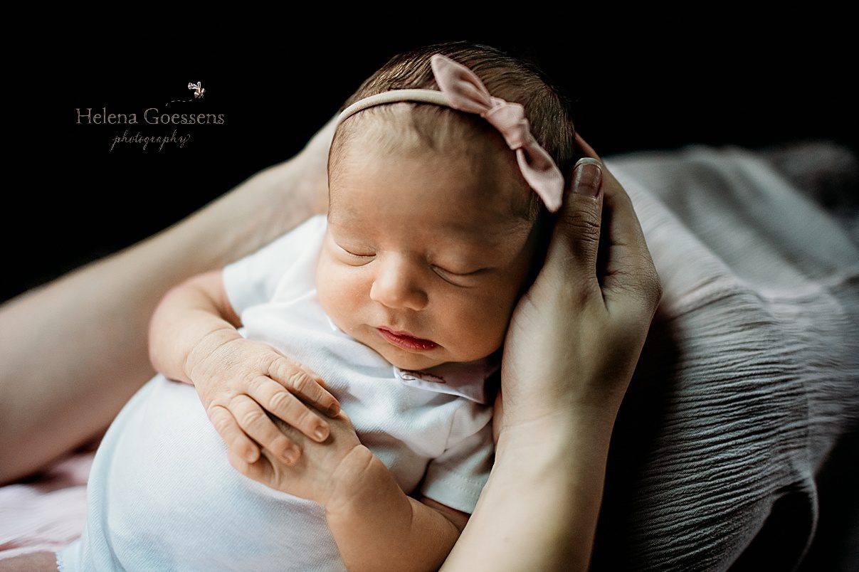 baby girl sleeps in mom's lap sitting on couch during lifestyle newborn photos at home