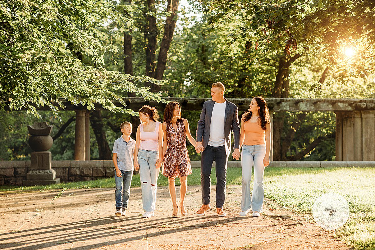 family of five holds hands walking through Larz Anderson Park during fall family photos