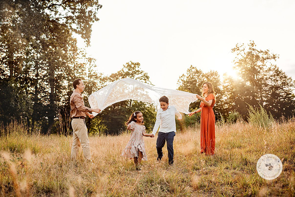 parents lift blanket over kids as they run under it during fall family photos 