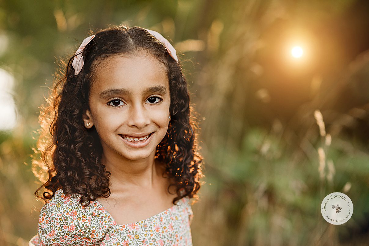 girl smiles in front of field at sunset during Concord MA family portrait session in the fall