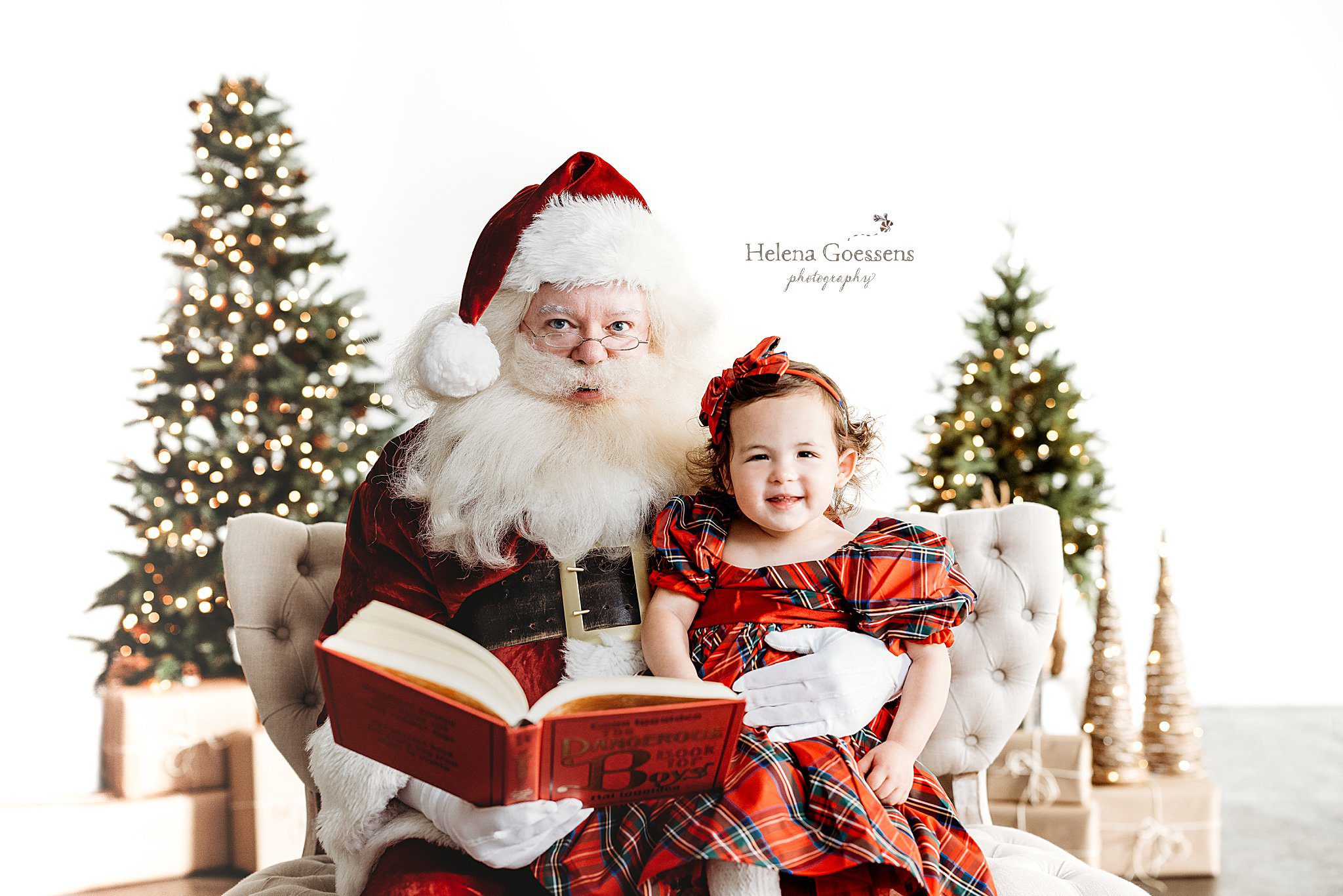 Santa reads to girl in red and green plaid dress for Studio Santa Portraits in Norwood, MA