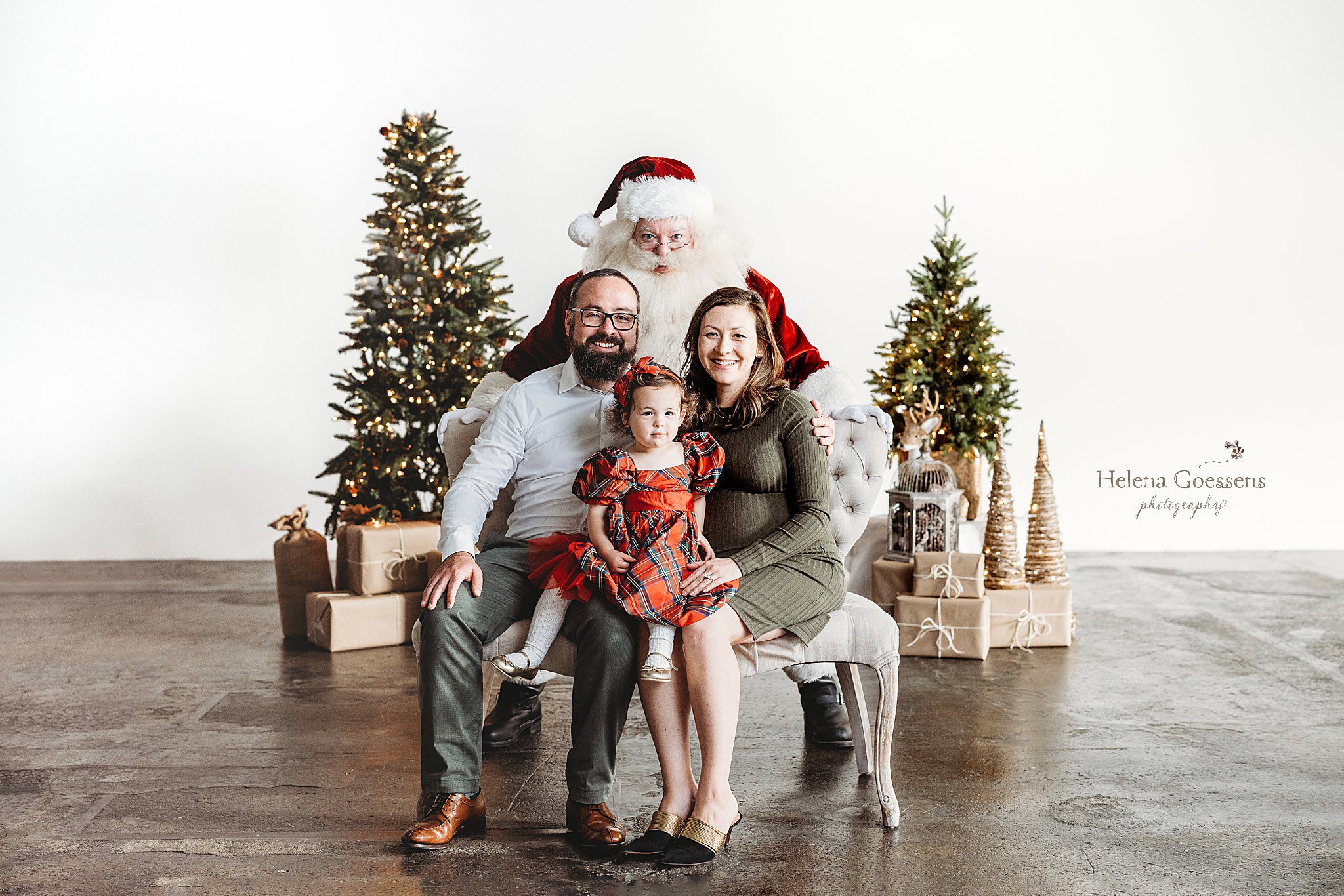parents sit with daughter in red plaid dress during Studio Santa Portraits in Norwood, MA