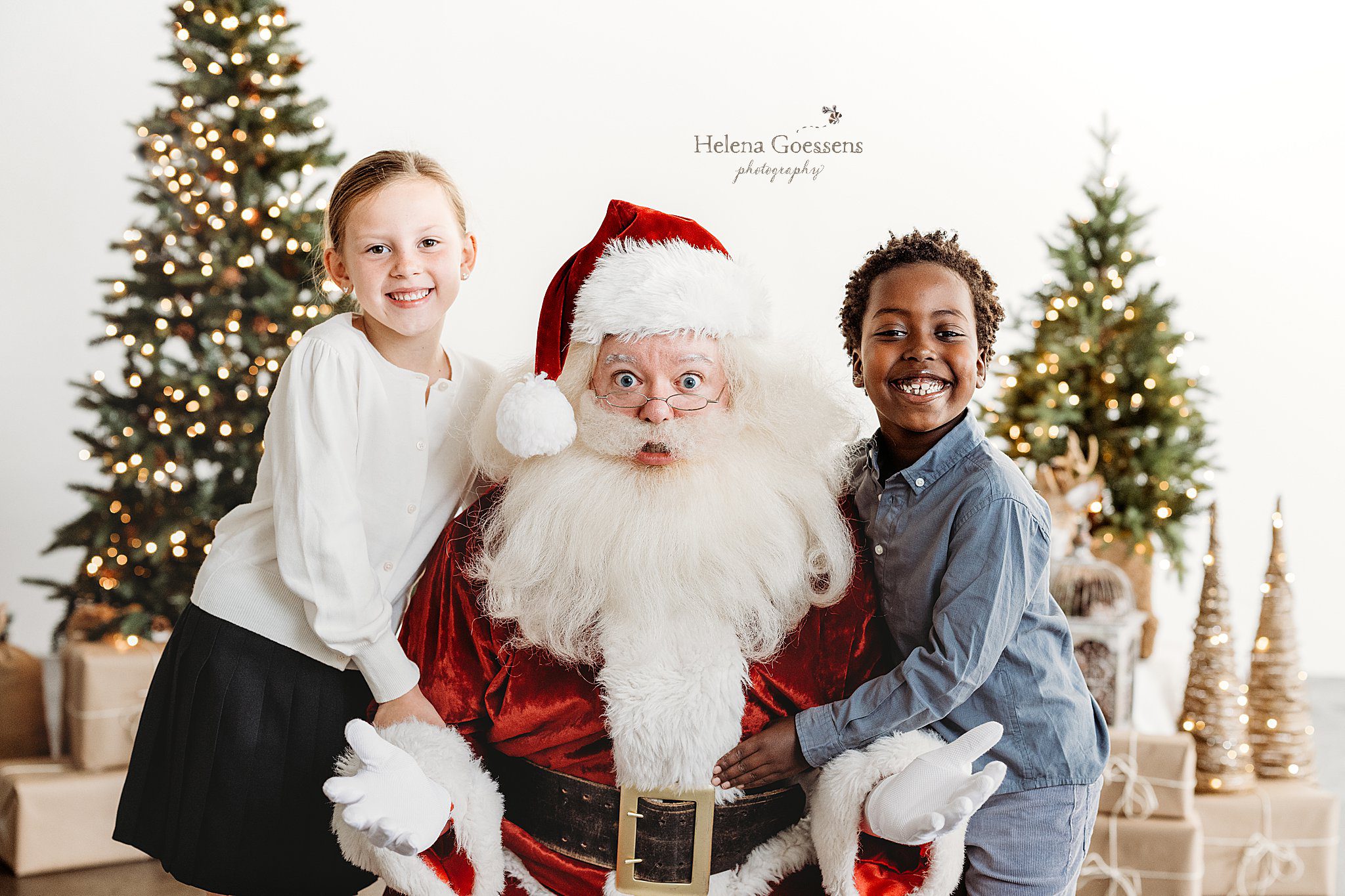 Santa smiles with two siblings during Studio Santa Portraits in Norwood, MA
